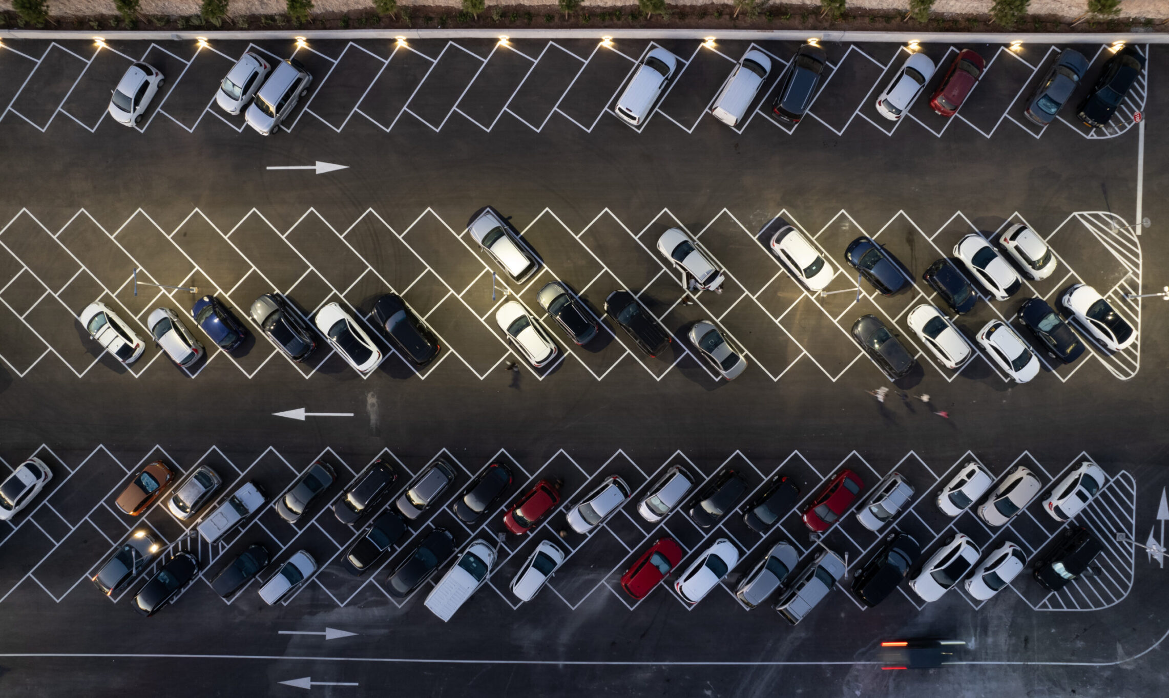 Drone aerial view of parking lots with cars at night. Crowded shopping mall car park.